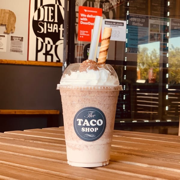 A The Taco Shop branded milkshake with whipped cream, a Ferrero Rocher, and a wafer roll.